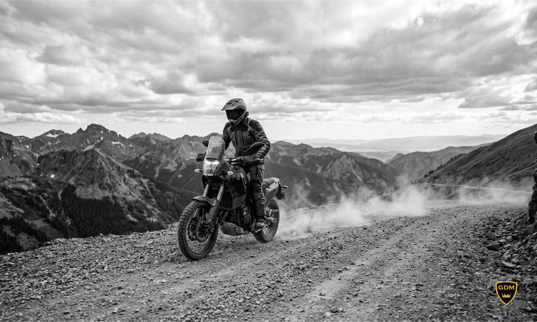 Adventure rider in a dual sport helmet riding a gravel mountain trail