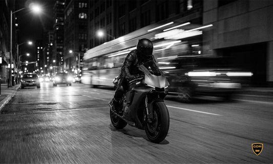 Rider in a matte black full face helmet riding a sport bike through a city street at night
