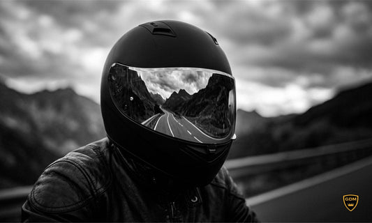 Rider in a full face helmet with a mirrored visor reflecting a mountain road
